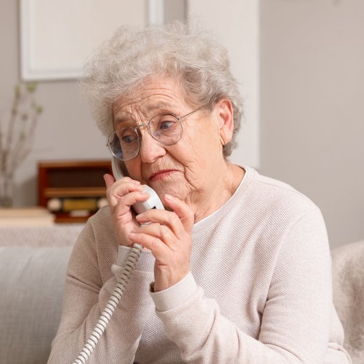 Elderly lady showing a worried look while talking on the phone.