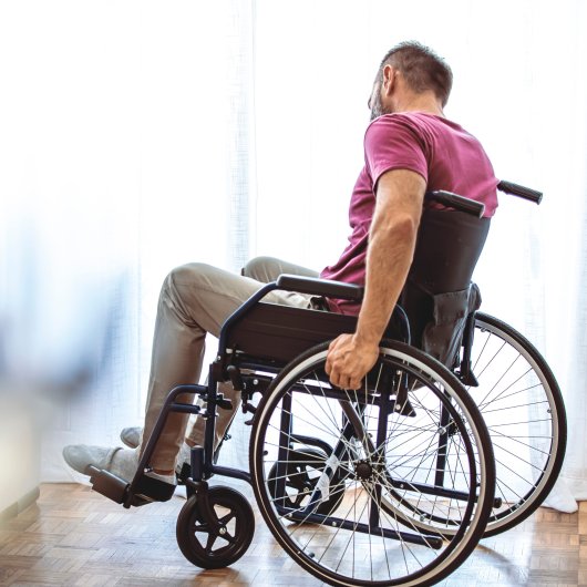 Homme assis et tenant les roues de son fauteuil roulant.