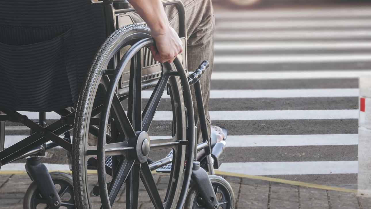 Personne en fauteuil roulant sur un trottoir de stationnement