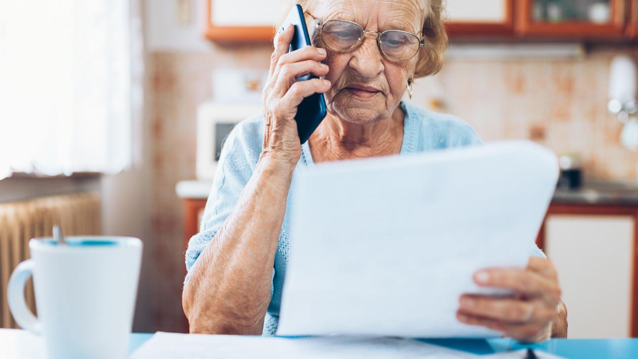 Dame âgée tenant une feuille et parlant au téléphone