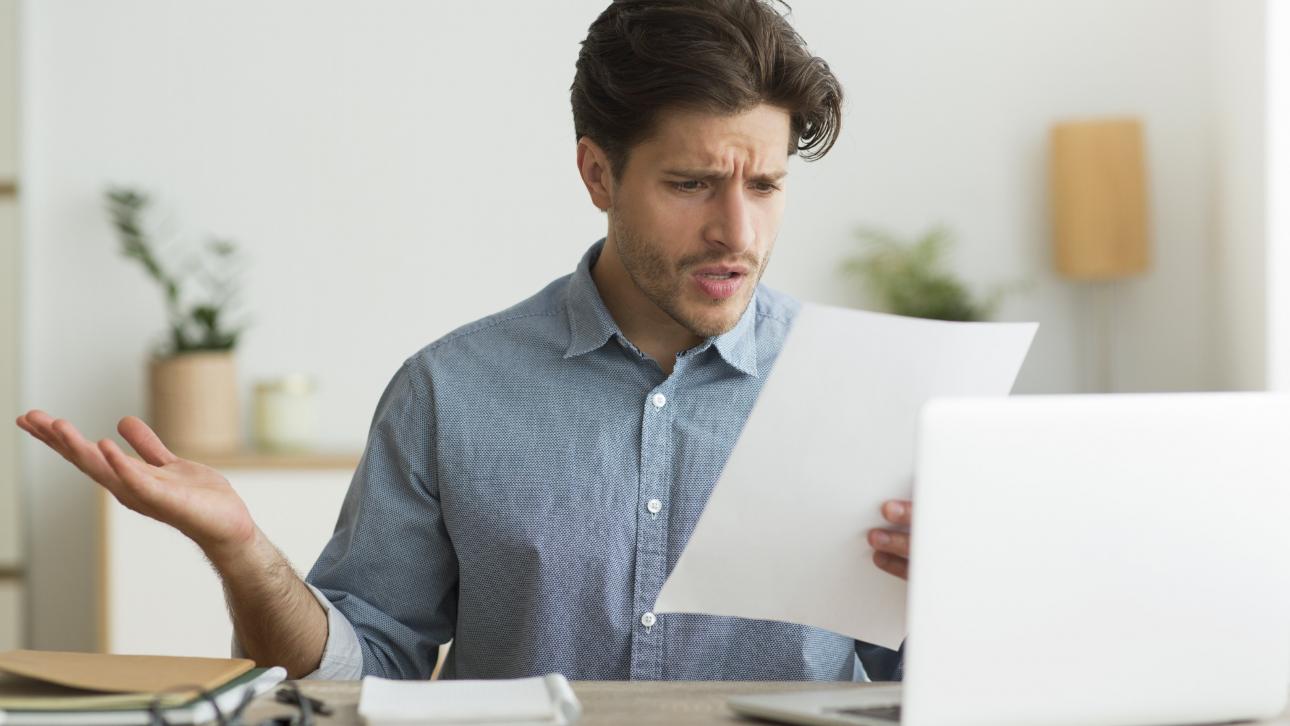Homme consultant un document l'air contrarié