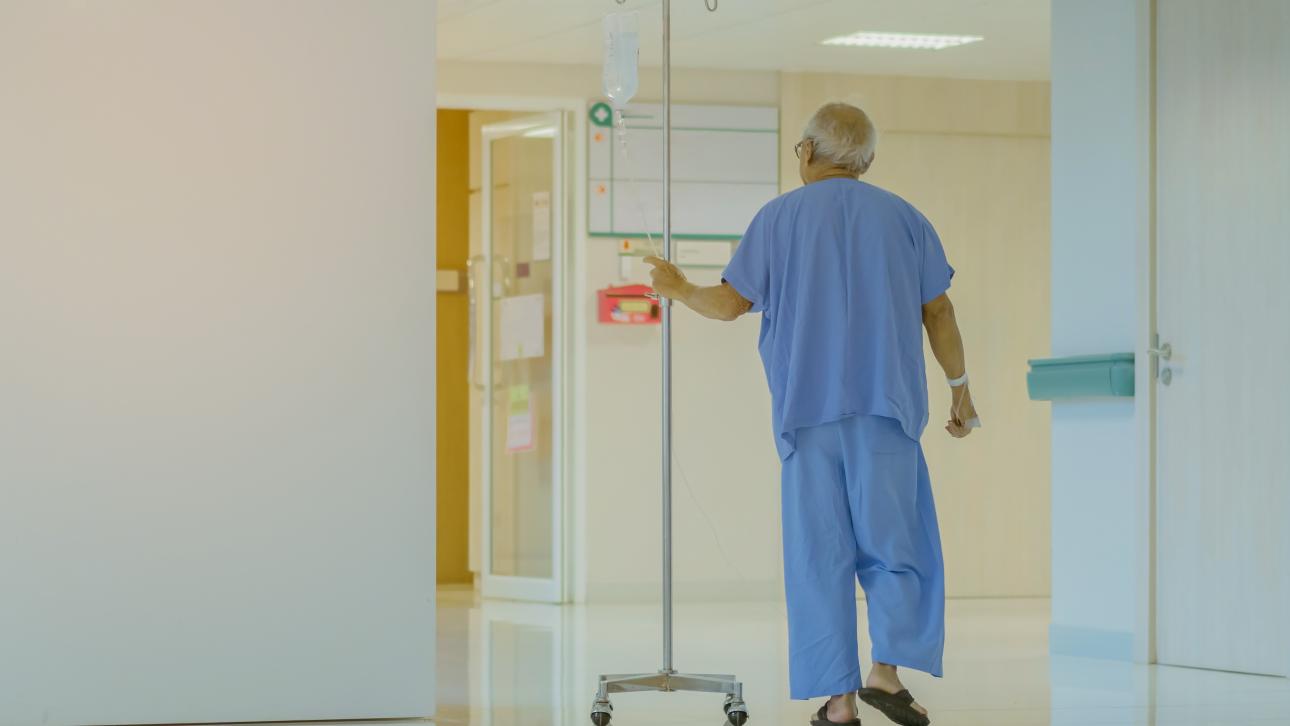 Vieillard marchant dans un corridor d'hôpital avec son soluté