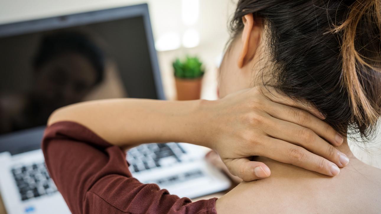 Femme regardant un ordinateur en massant son cou douloureux