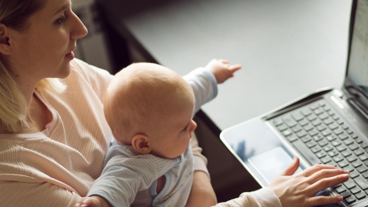 Mère travaillant à l'ordinateur en tenant son bébé