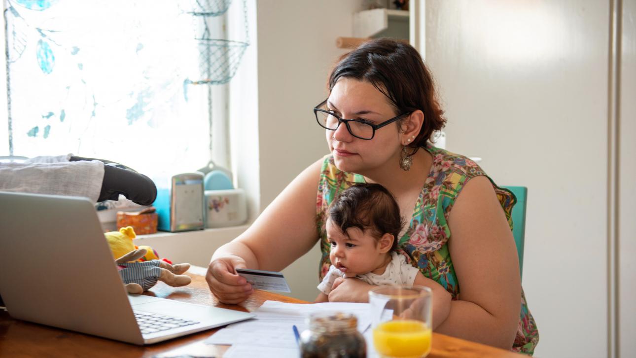 Mère effectuant un achat en ligne en tenant son bébé