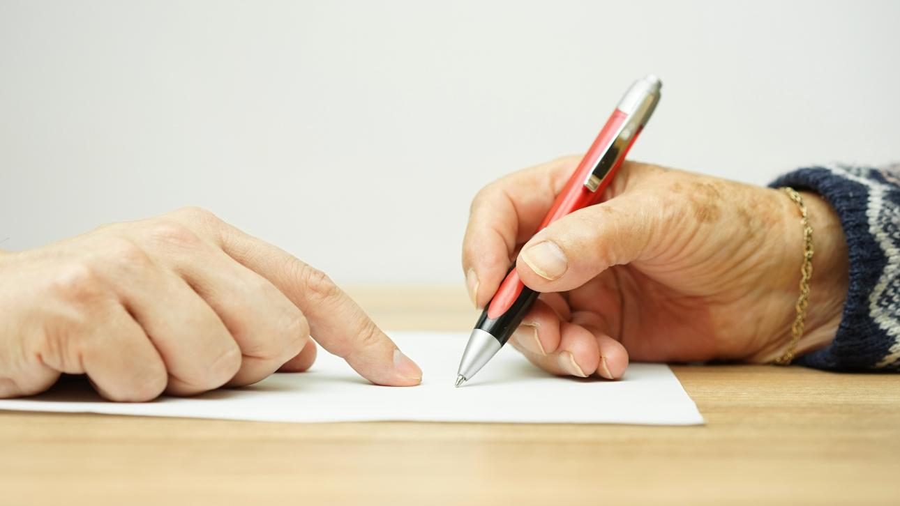 Personne âgée signant un formulaire