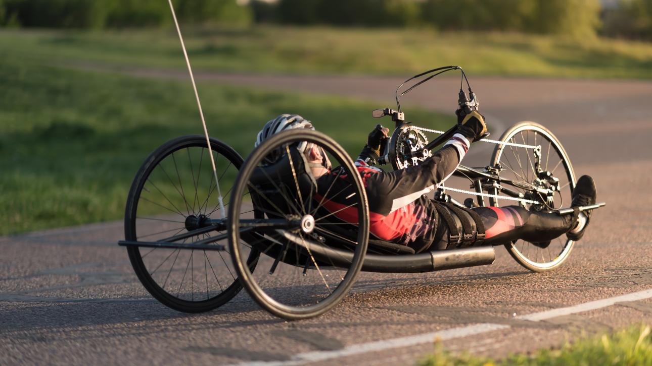 Homme conduisant un vélo à mains sur une route asphaltée