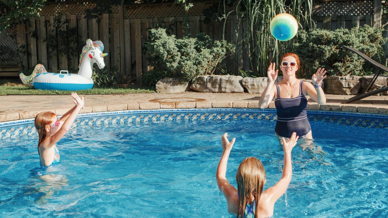 Femme jouant au ballon dans la piscine avec deux enfants