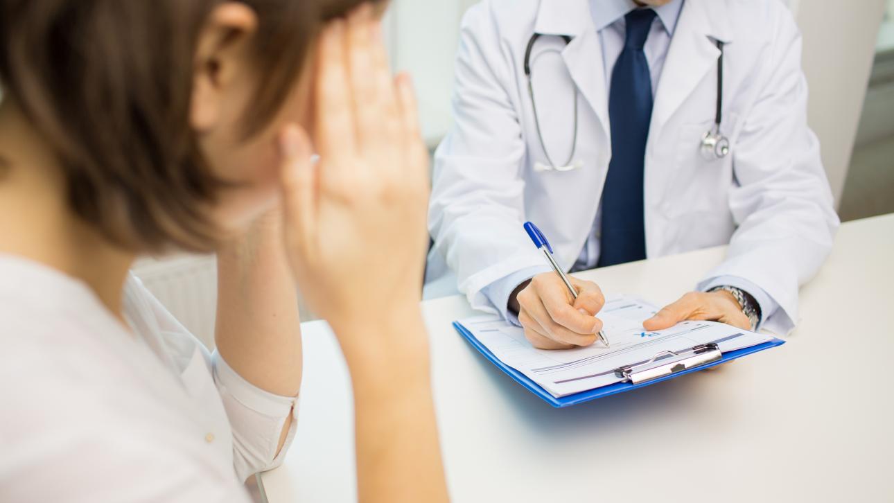 Femme consultant un médecin en se tenant la tête