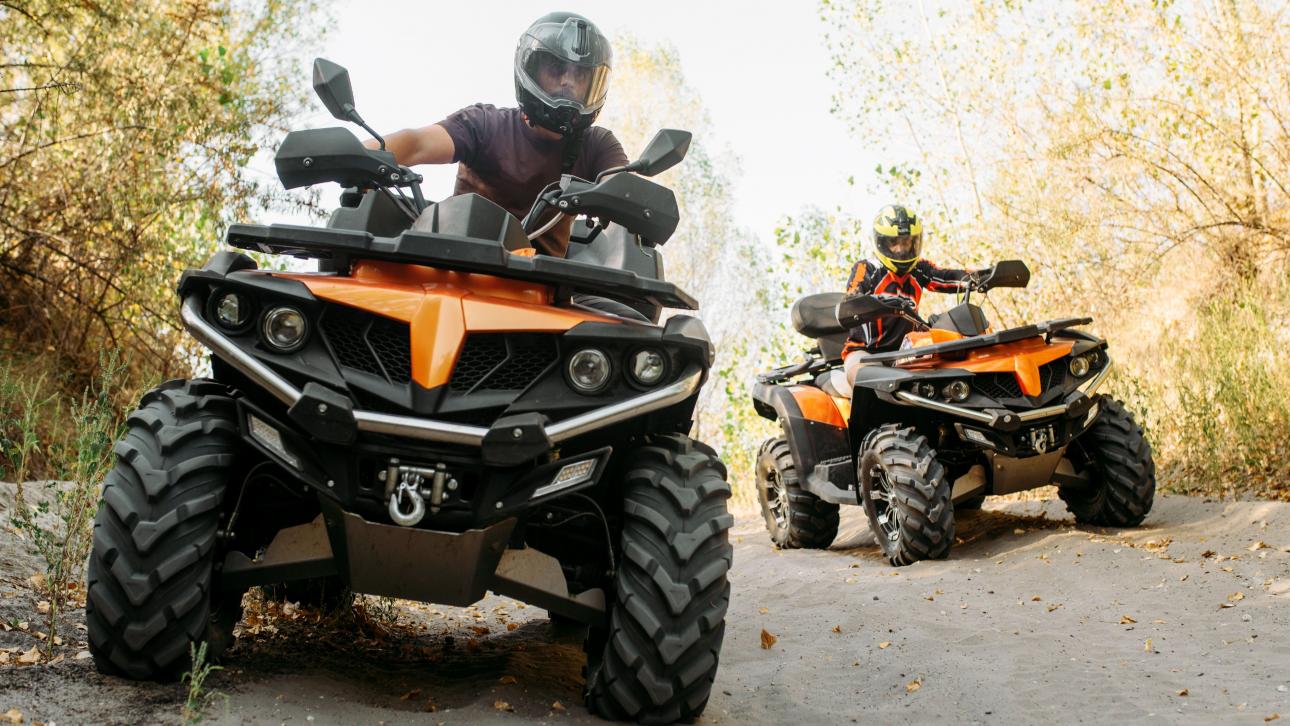 Deux personnes conduisant un quatre-roues dans un sentier