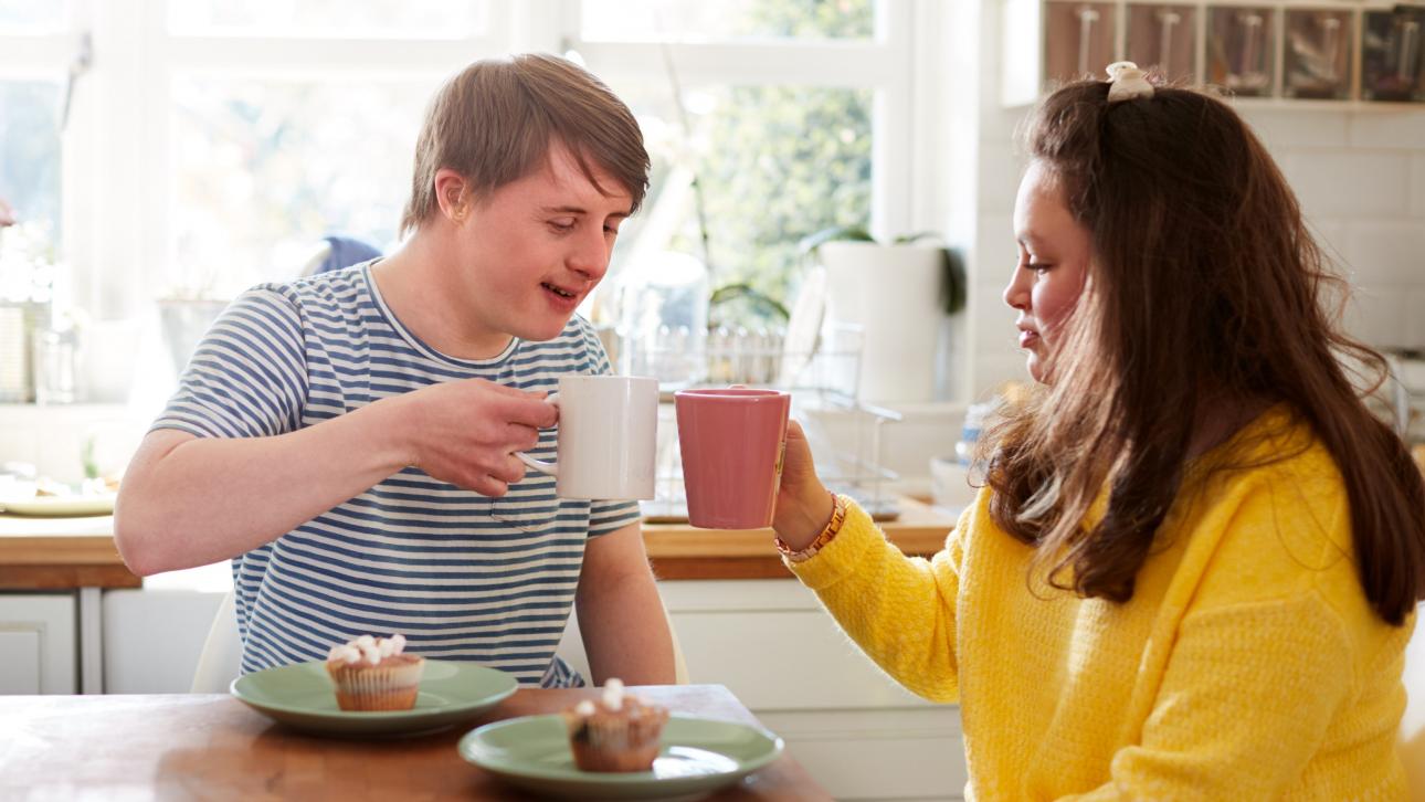 Jeune homme atteint de trisomie buvant un café avec sa mère