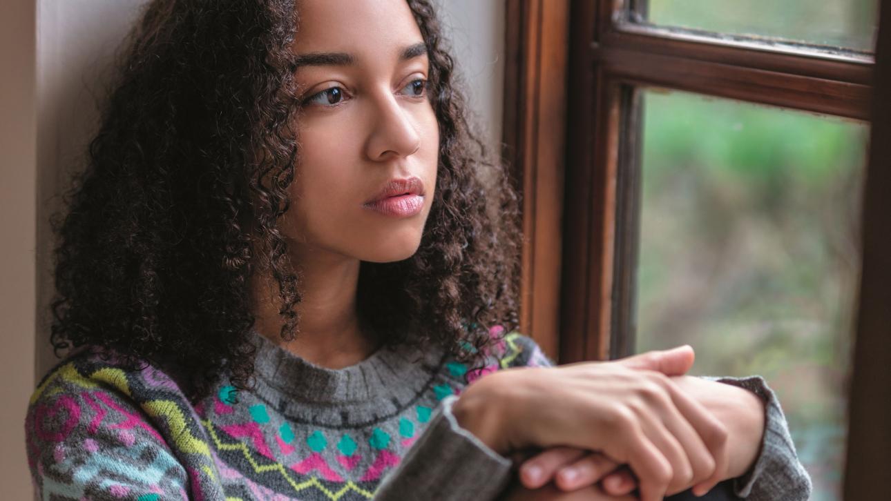 Adolescente pensive assise près d'une fenêtre