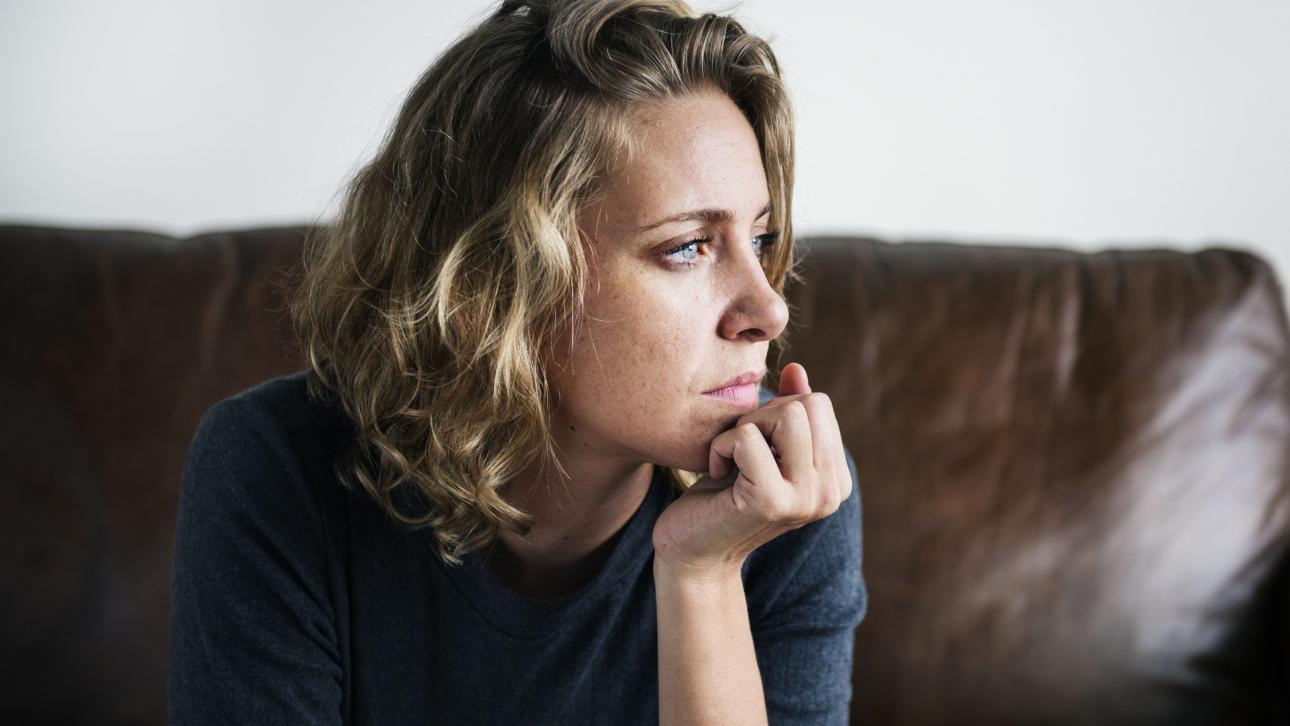 Jeune femme assise sur un divan et regardant au loin