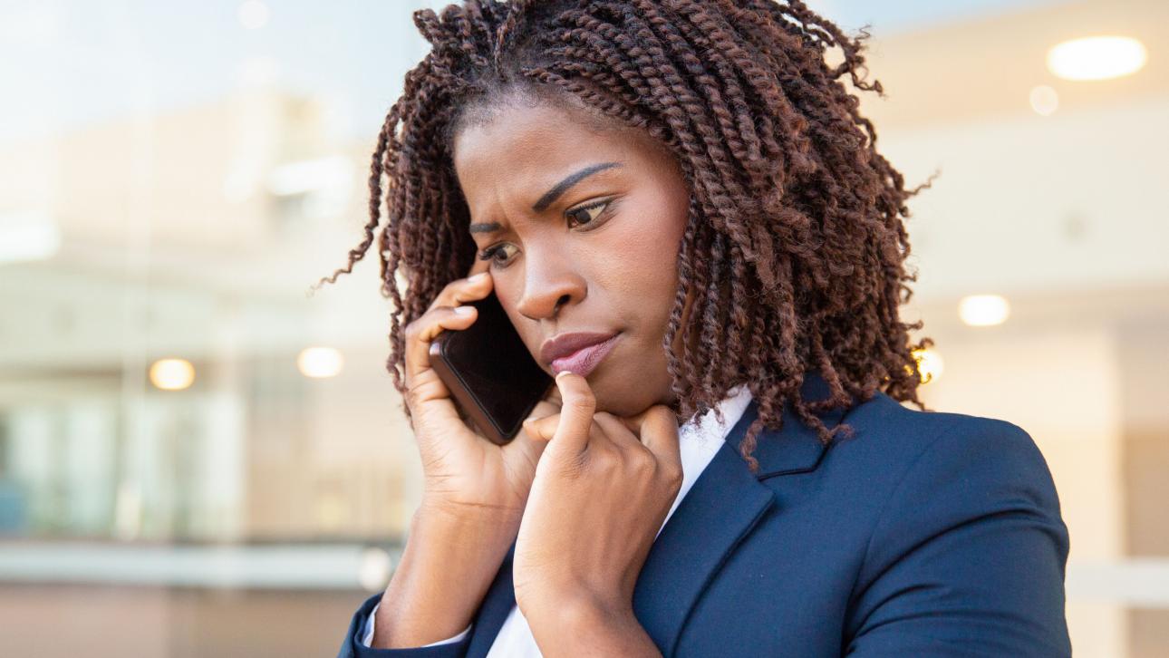 Jeune professionnelle arborant un air inquiet en parlant au cellulaire