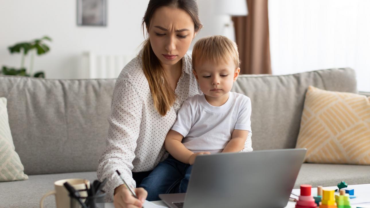 Jeune maman prenant des notes avec son enfant assis sur ses genoux