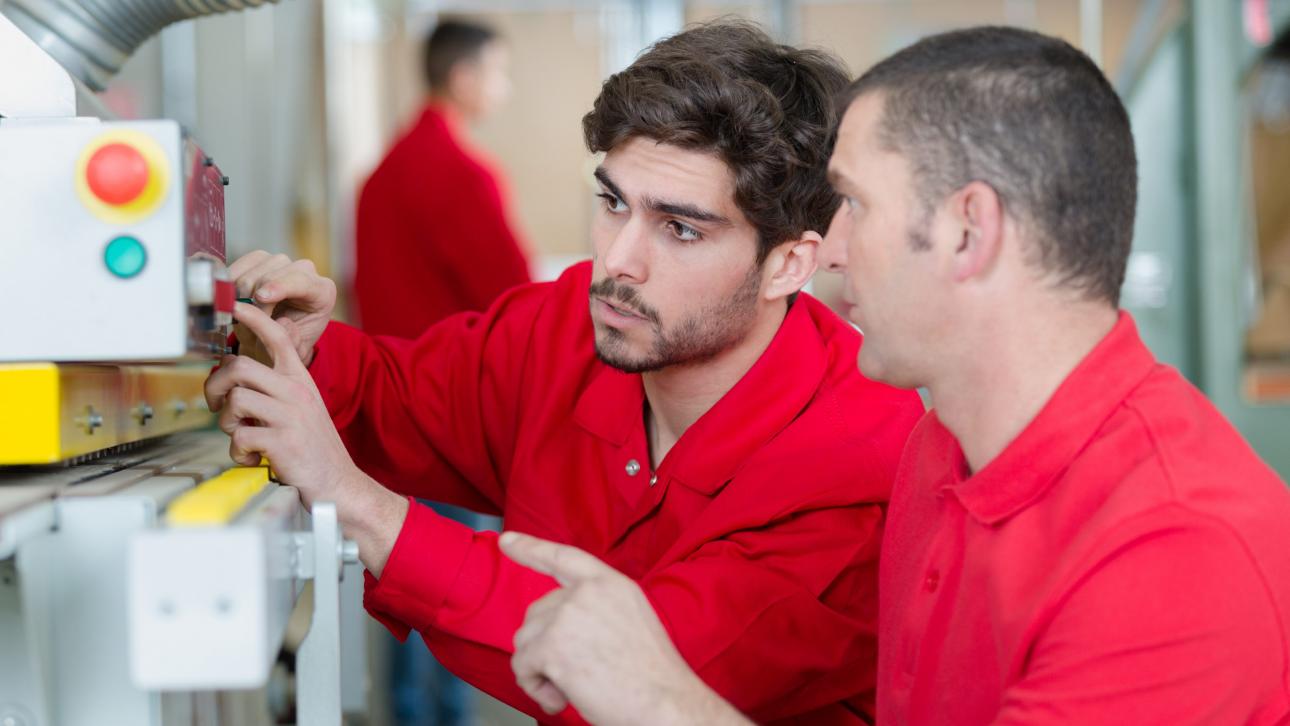 Un enseignant montre à un stagiaire comment utiliser une machine