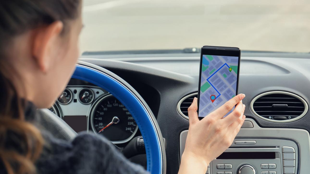 Femme plaçant son cellulaire sur un support fixé au tableau de bord de sa voiture