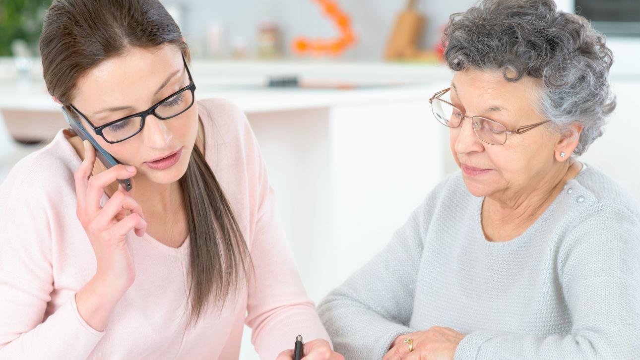 Woman talking on the phone sitting next to an elderly lady