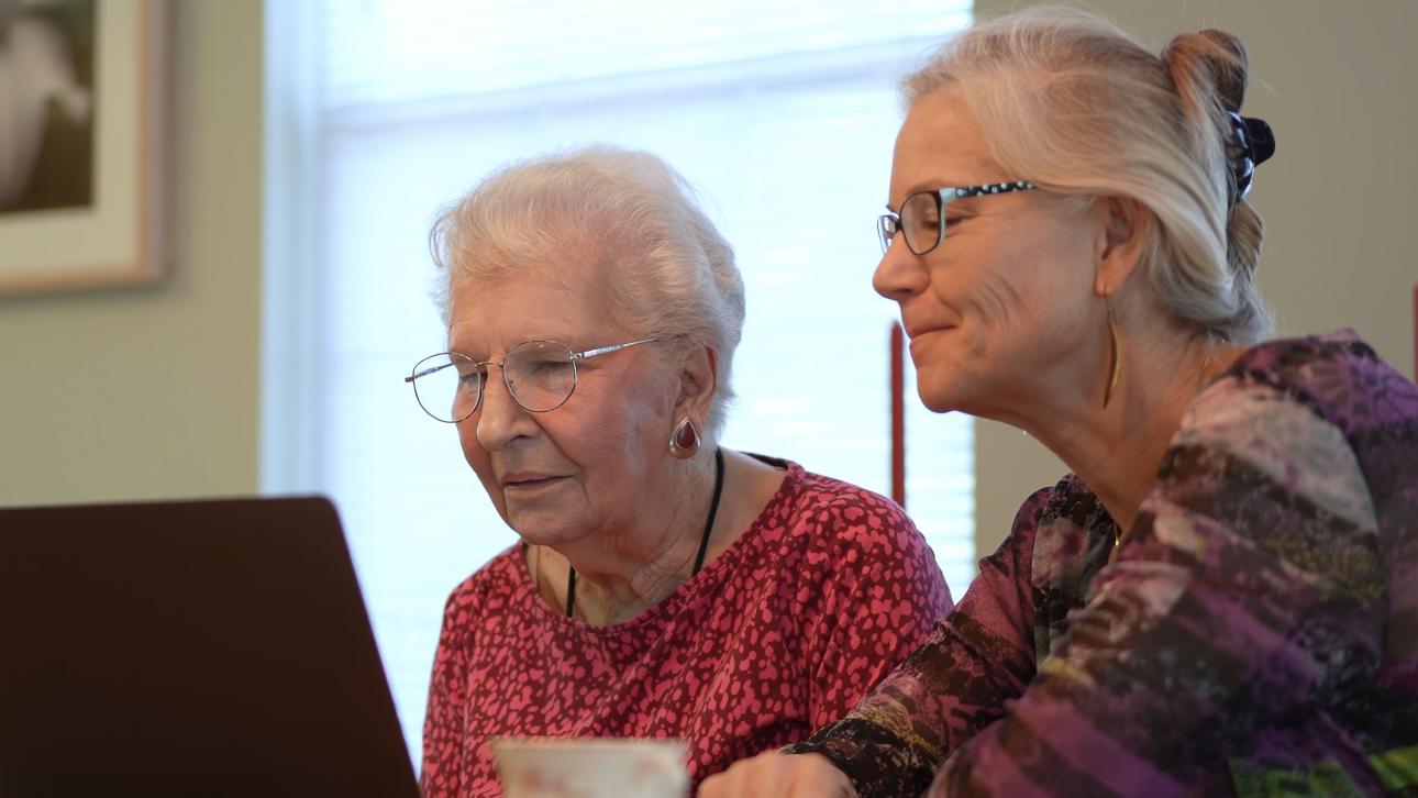 An elderly woman and her mother look at a computer screen