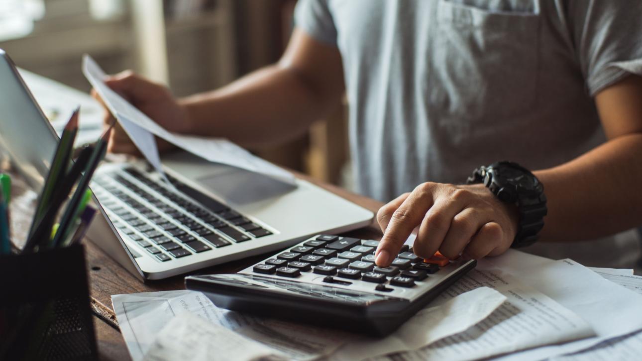 Man looking at tax documents using his calculator