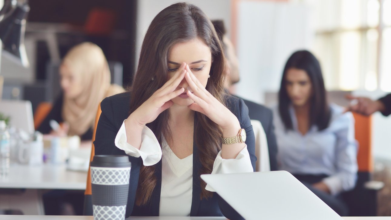 Woman showing a sad look in the office while her colleagues are working
