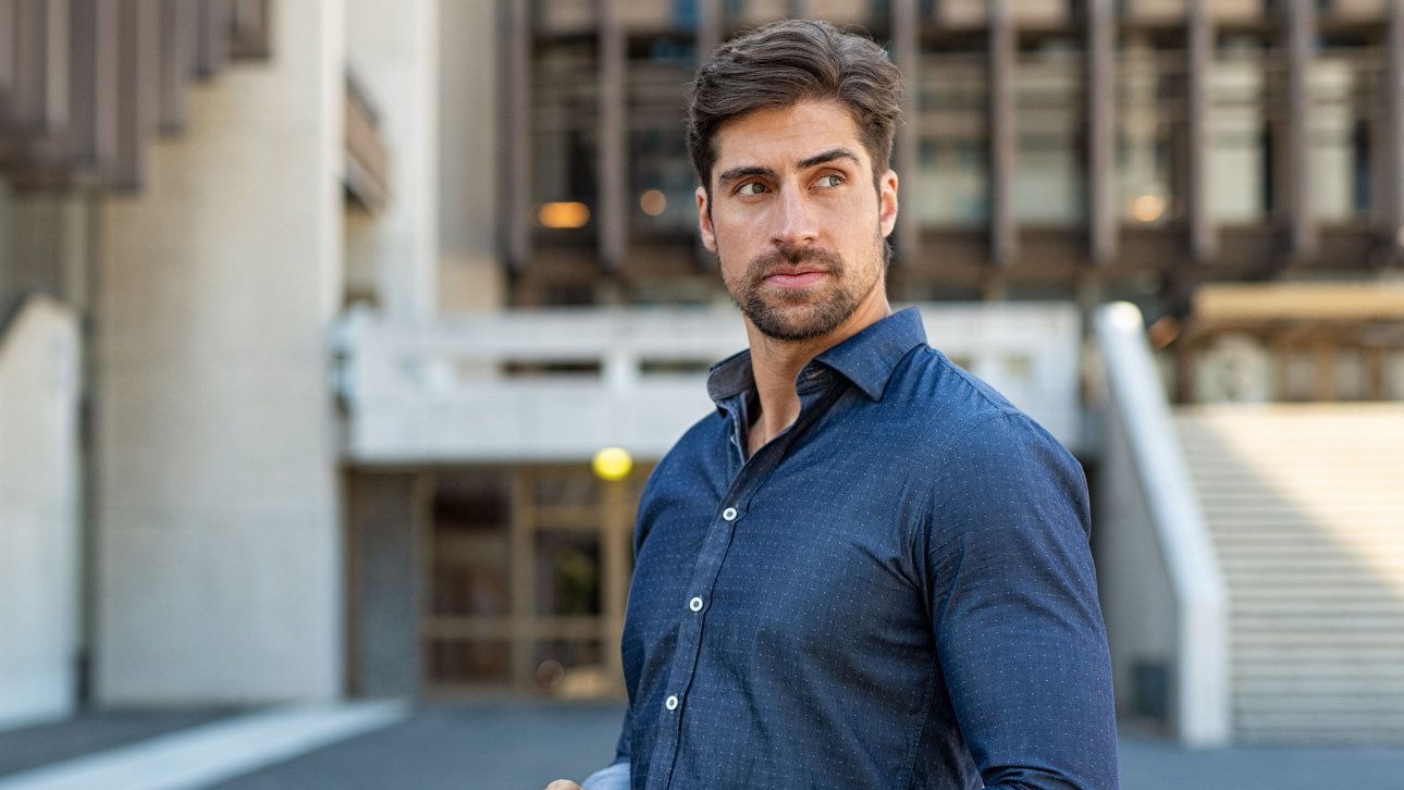 Man holding his cell phone and looking away with a worried look