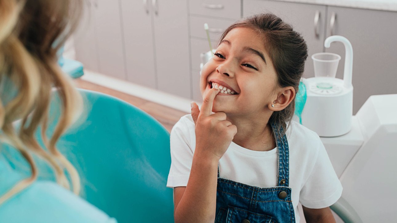 Little girl proudly showing her teeth to her dentist