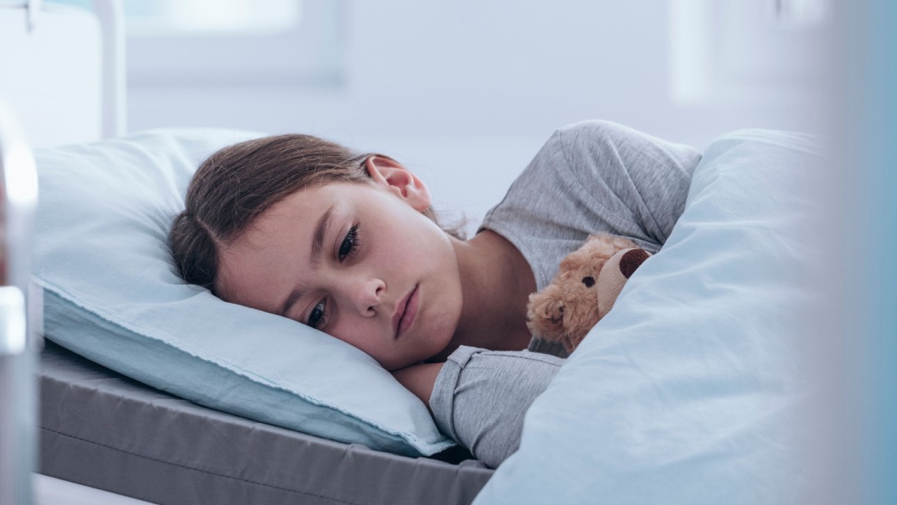 Little girl lying in a hospital bed looking sad