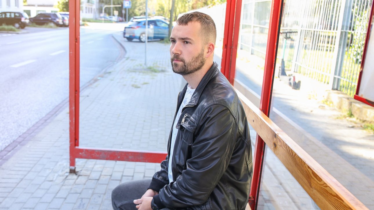 Citizen seated at a bus stop.