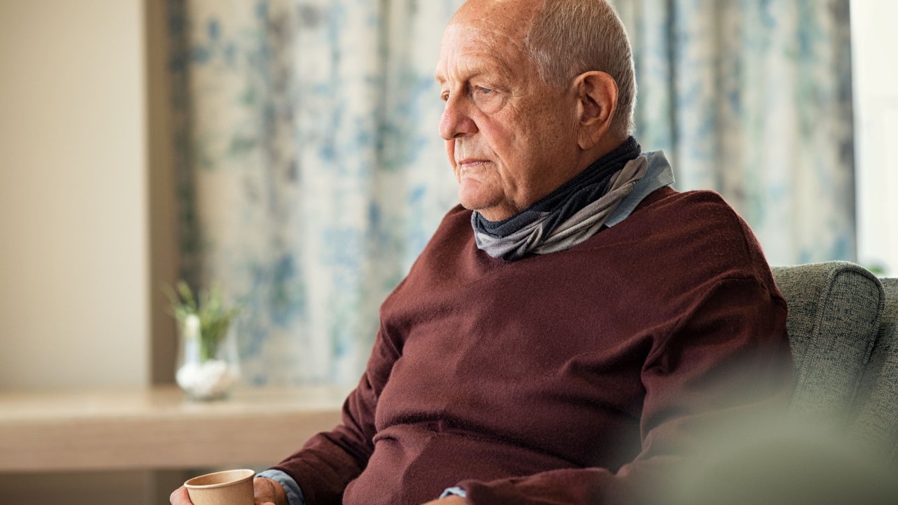 Lonely and vulnerable elderly man sitting in an armchair