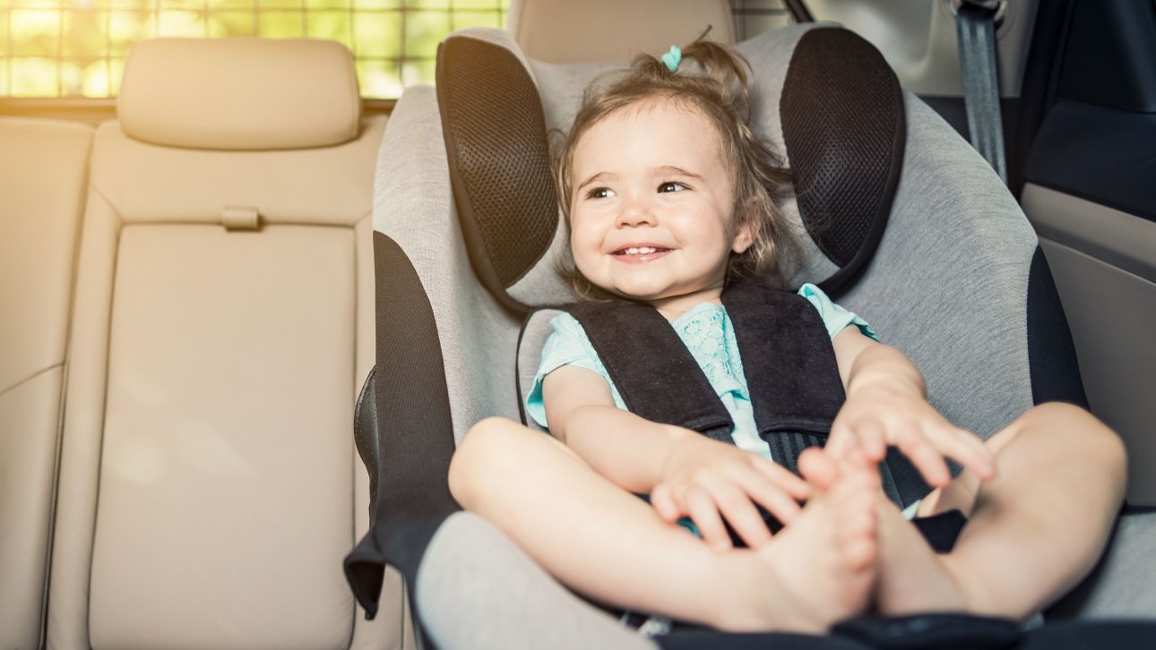 Smiling little girl sitting in child car seat