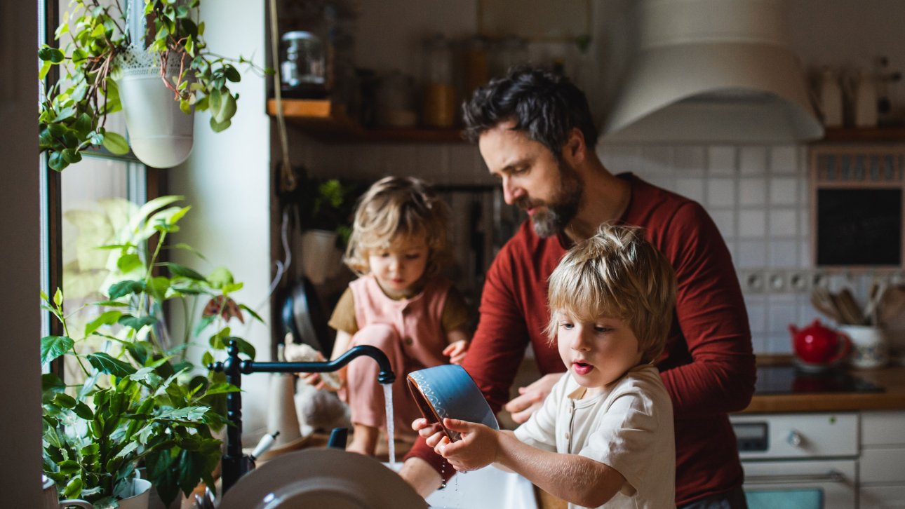 A father washes dishes with his two young children