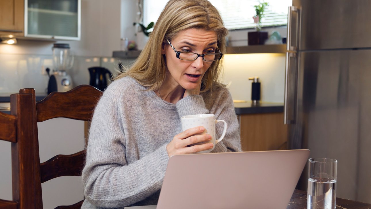 Femme qui regarde l'écran de son ordinateur d'un air surpris.