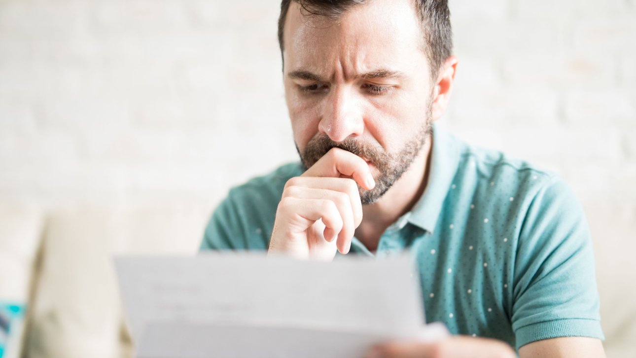 Homme consultant une facture en affichant un air sérieux.