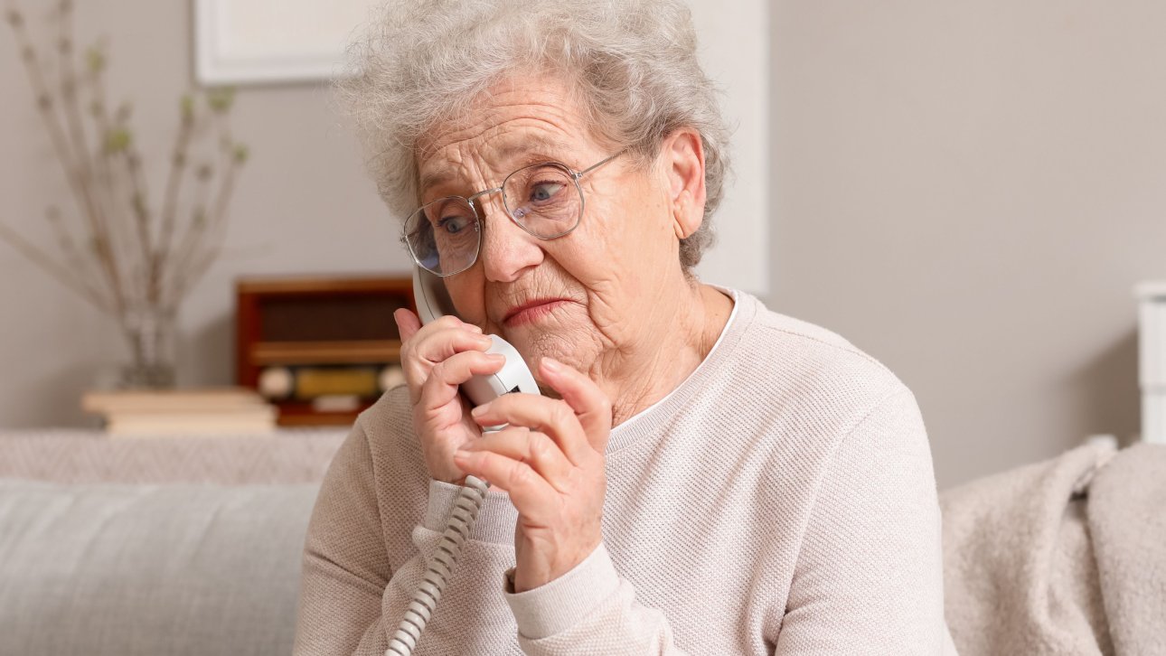 Elderly lady showing a worried look while talking on the phone.