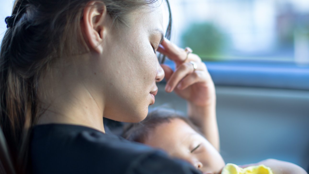 Worried mother holding her sleeping child in her arms.