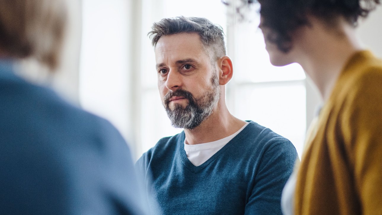 Man with tired eyes participating in group therapy.