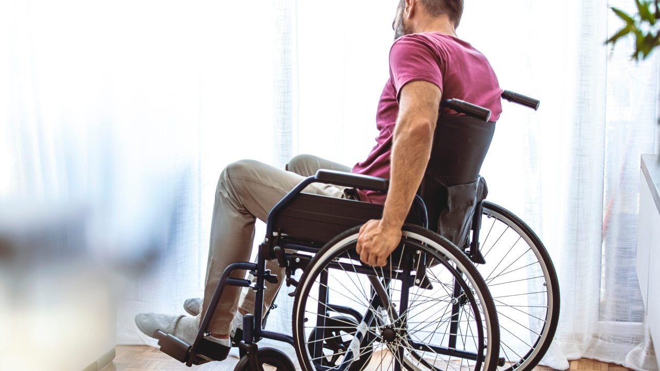 Homme assis et tenant les roues de son fauteuil roulant.