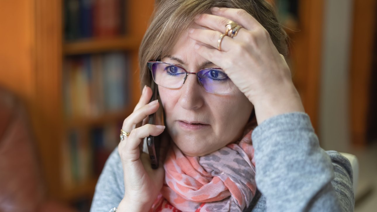 Femme inquiète posant une main sur son front en parlant au téléphone.