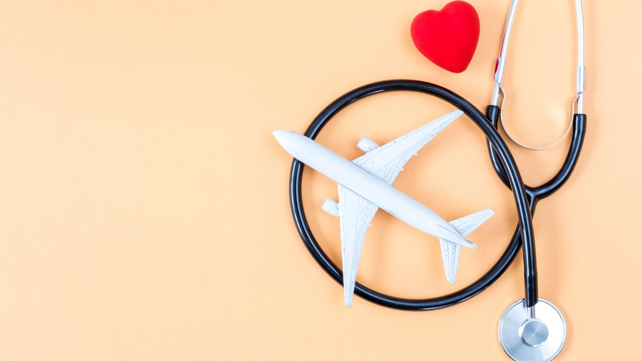 Tiny plane placed near a stethoscope and a small red heart.