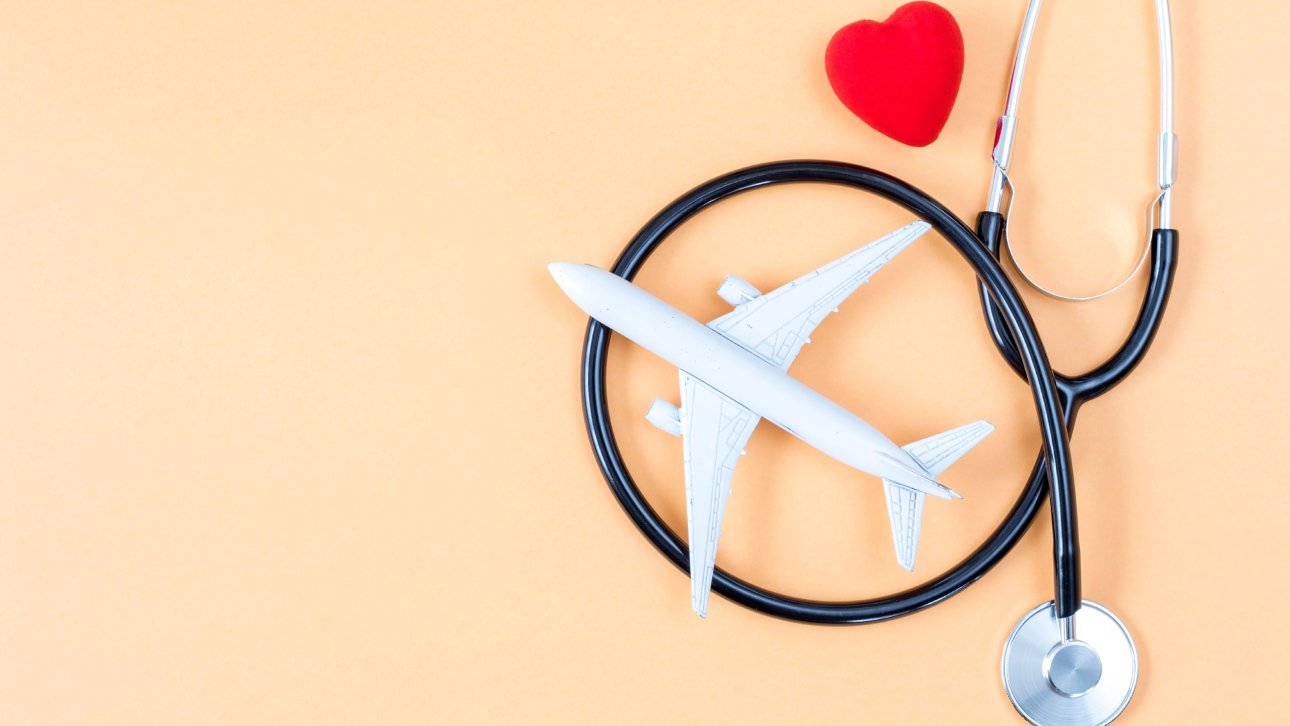 Minuscule avion posé près d'un stéthoscope et d'un petit cœur rouge.