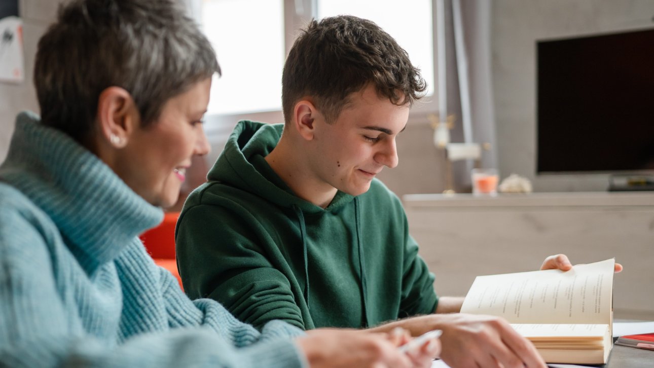 A mother helps her teenager who studies at home.