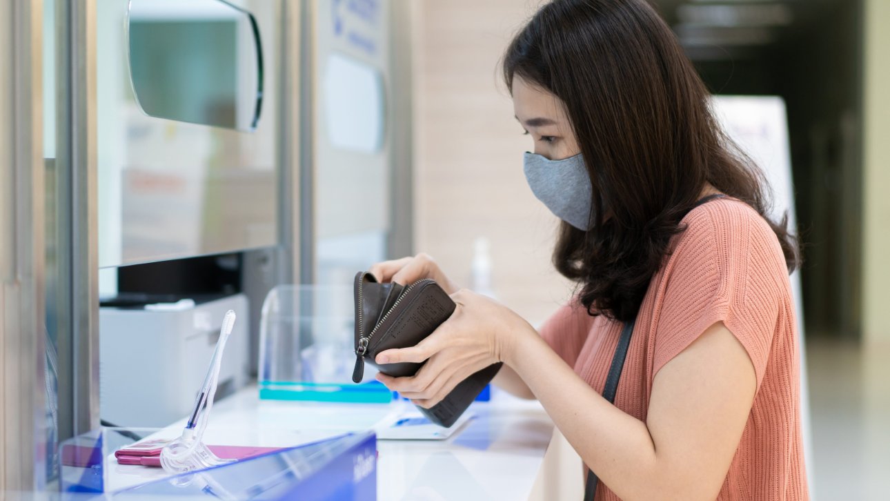 Femme cherchant une carte dans son portefeuille devant le comptoir de la réception de l'hôpital.