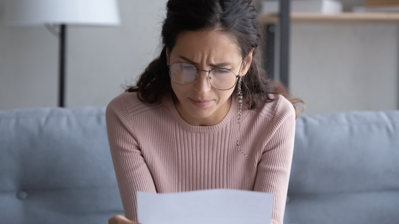 Woman sitting on a sofa reading a letter.