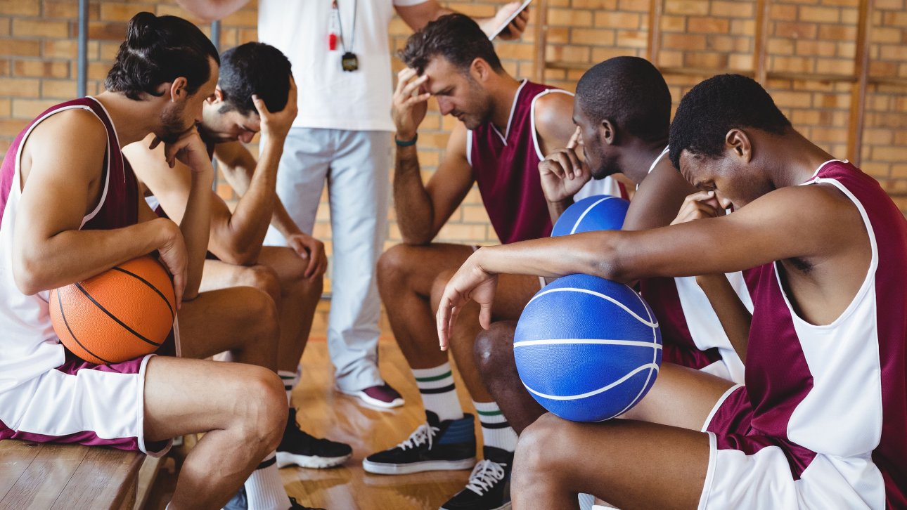 A coach talks to basketball players who look sad.