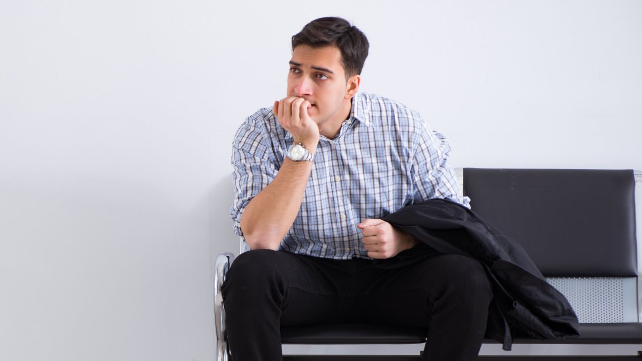 Un homme anxieux patiente assis sur une chaise d'une salle d'attente.