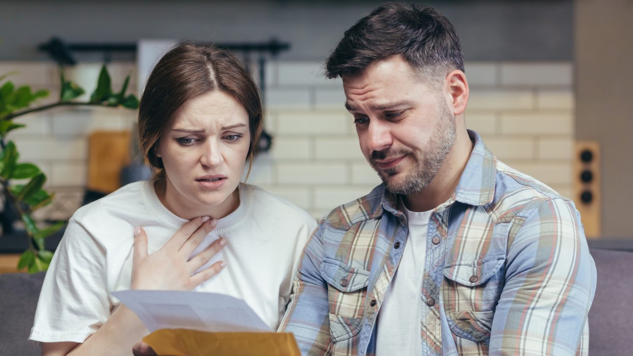 Couple lisant une lettre en affichant un air étonné et triste.