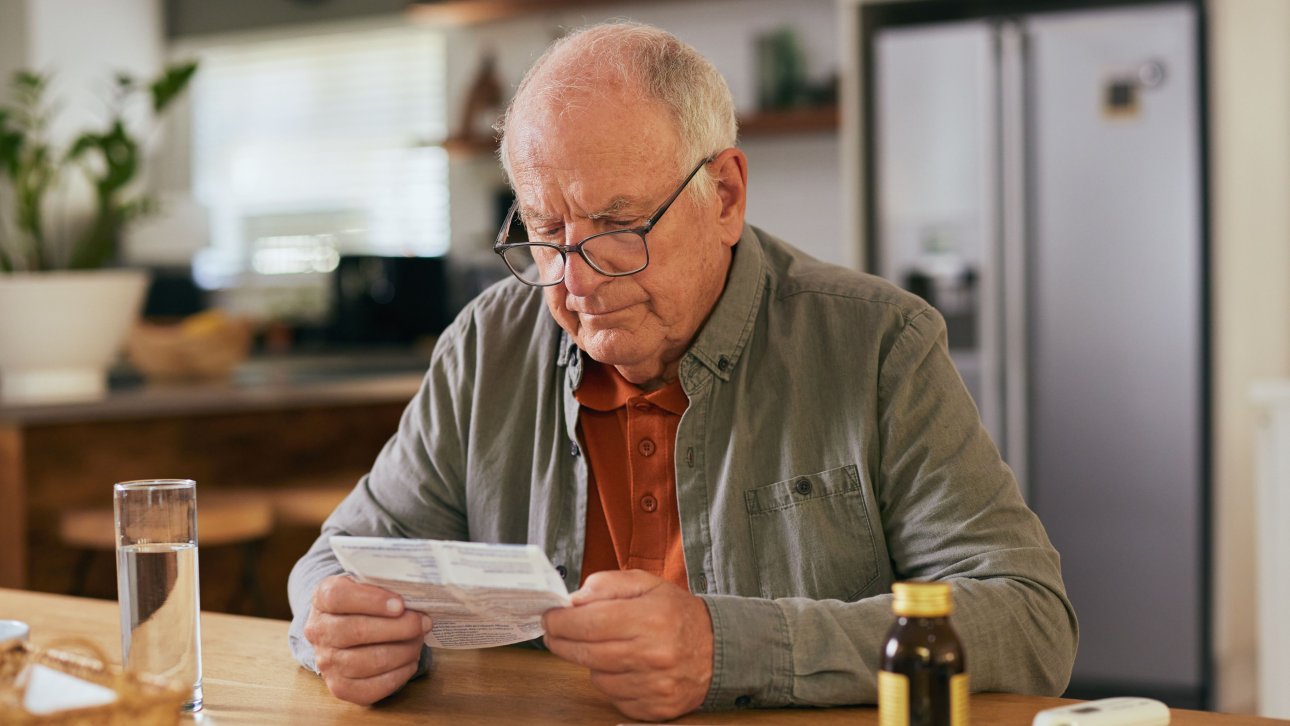 Un aîné de plus de 65 ans lit des indications concernant un médicament.