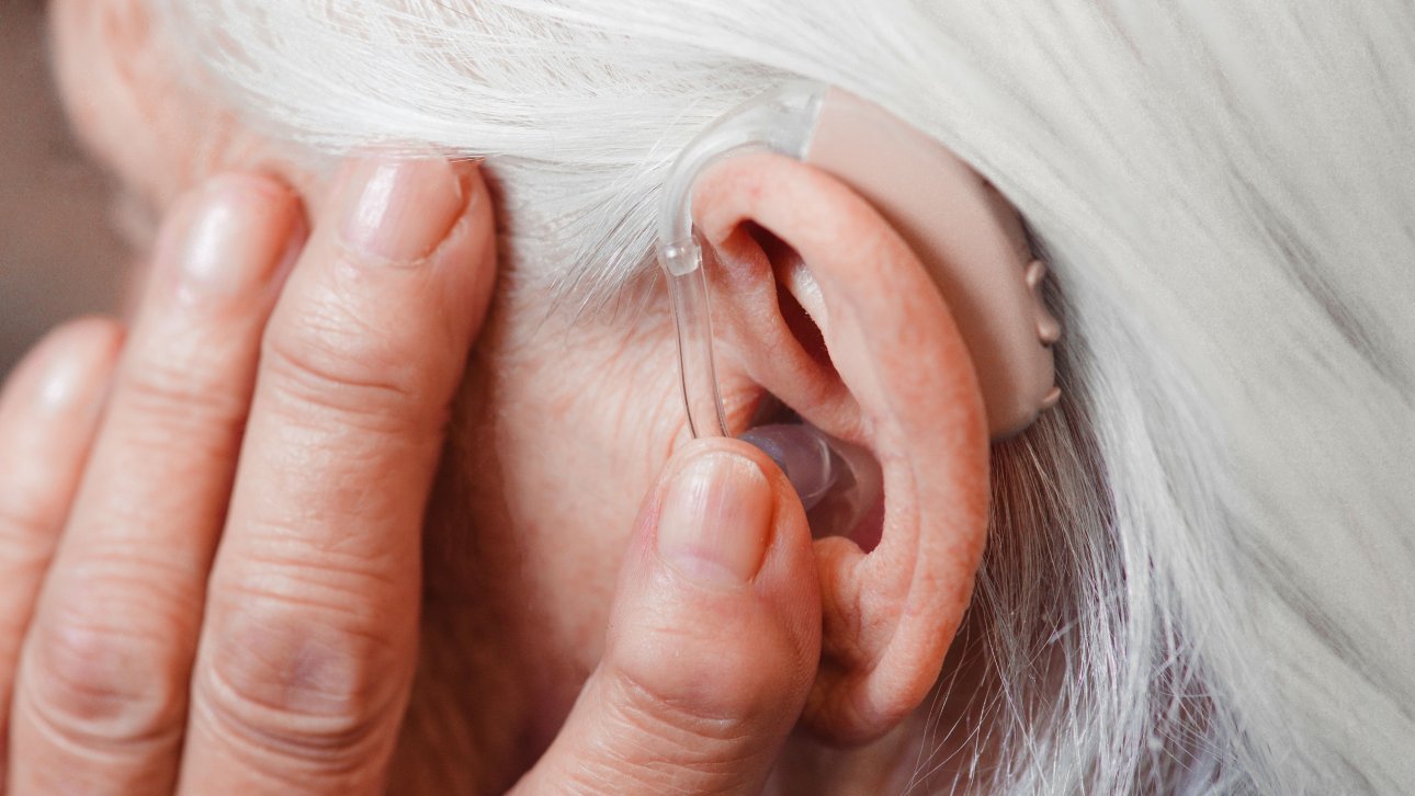 A close-up of a woman’s ear wearing a hearing aid designed for her hearing loss.