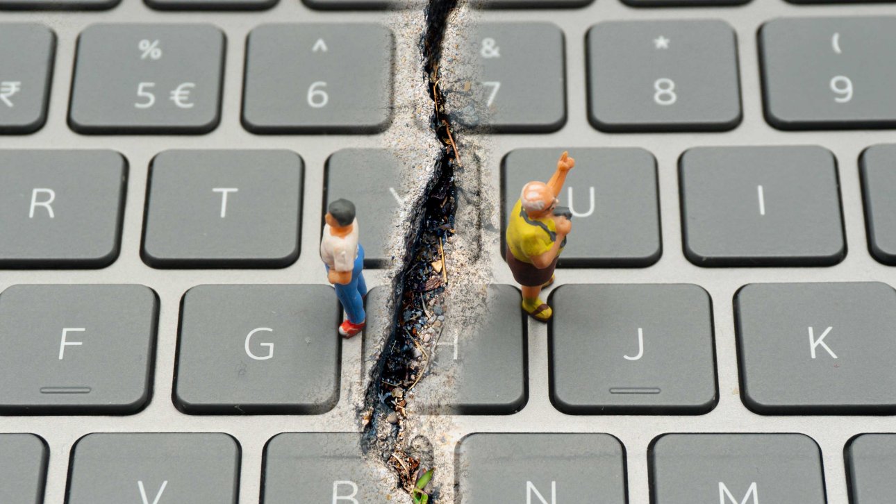 Deux figurines posées sur un clavier d'ordinateur sont séparées par une profonde fissure.